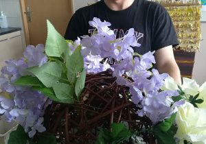 Marcin ze swoją kompozycją kwiatową w kuli ratanowej.
